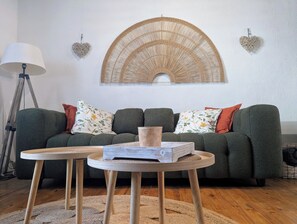 A living room with a green sofa, two round wooden tables, a lamp, and decorative wall art. - La Glycine, bastide du XIIIe (Montjoi)