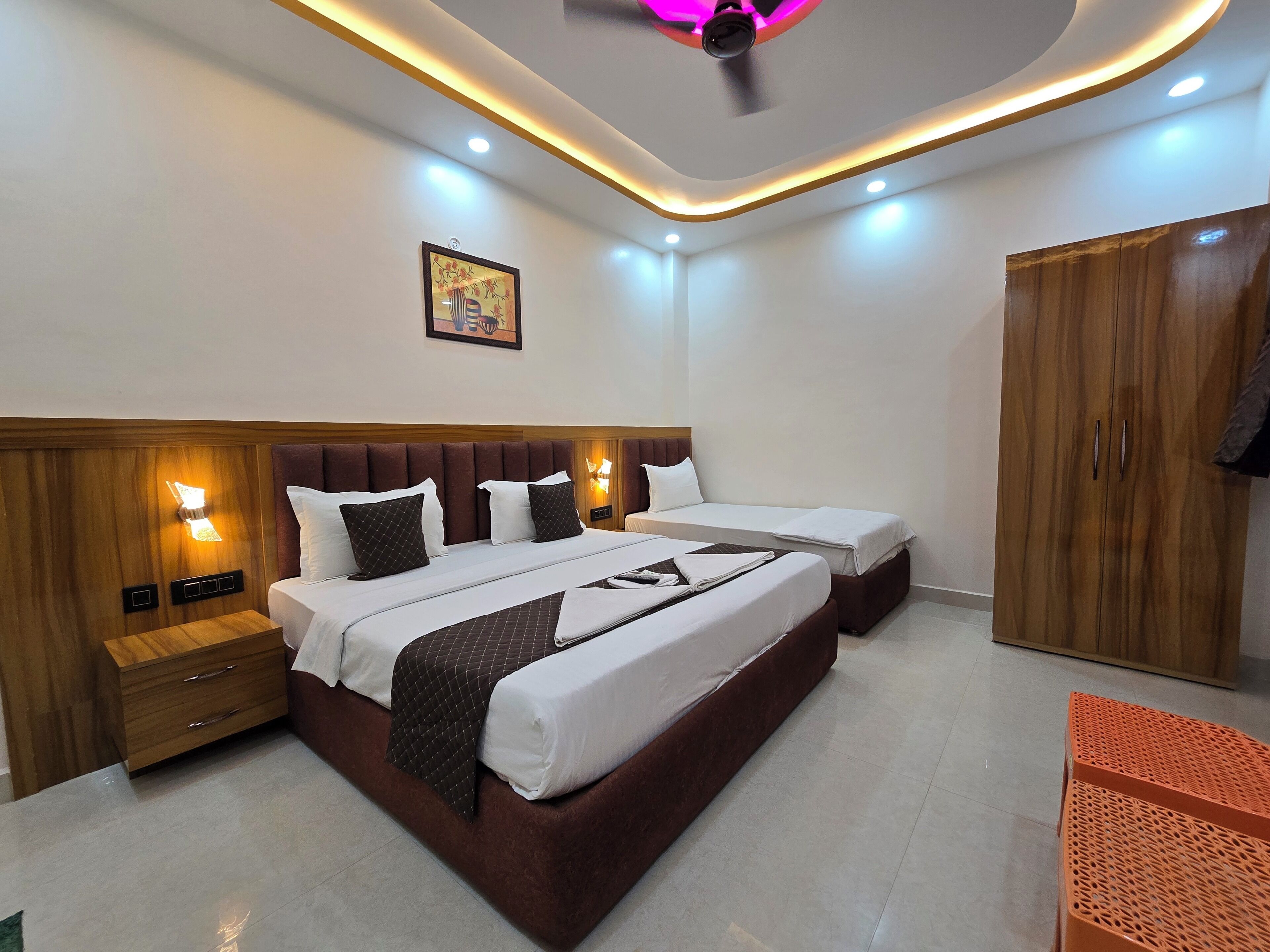 A hotel room with a large bed, bedside tables, a wardrobe, and a ceiling fan.