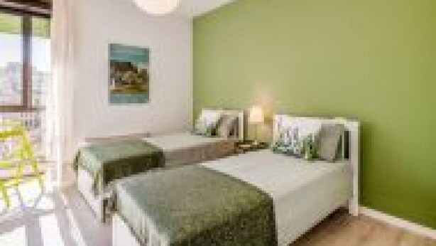 A bedroom with two beds, a window, and a green wall. - Our residence is located on the fourth floor of a building, with a lift.Service room which our guests can access complete with microwave, coffee machine, electric kettle, cups and glasses.Bicycle parking inside the building, only on specific request.Poss (Padua)
