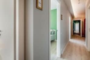 A hallway with a wooden floor, a door on the left, and a green wall in the background. - Our residence is located on the fourth floor of a building, with a lift.Service room which our guests can access complete with microwave, coffee machine, electric kettle, cups and glasses.Bicycle parking inside the building, only on specific request.Poss (Padua)