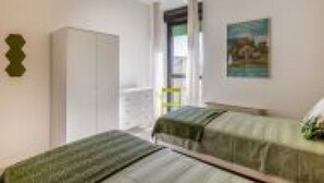 A bedroom with two beds, a wardrobe, and a painting on the wall. - Our residence is located on the fourth floor of a building, with a lift.Service room which our guests can access complete with microwave, coffee machine, electric kettle, cups and glasses.Bicycle parking inside the building, only on specific request.Poss (Padua)