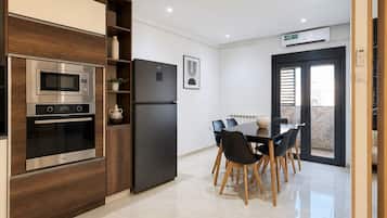 A modern kitchen with built-in appliances, a dining area with a table and chairs, and a sliding glass door leading to an outdoor area.