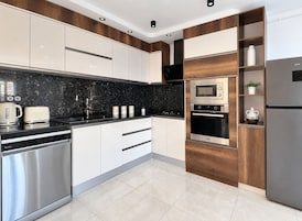 Una cocina moderna con electrodomésticos de acero inoxidable, encimera de granito negro y armarios de madera.