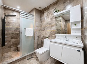 A modern bathroom with a glass-enclosed shower, a white toilet, and a vanity with a mirror.