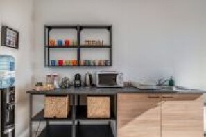 Uma cozinha moderna com micro-ondas, cafeteira e uma prateleira com diversos objetos.