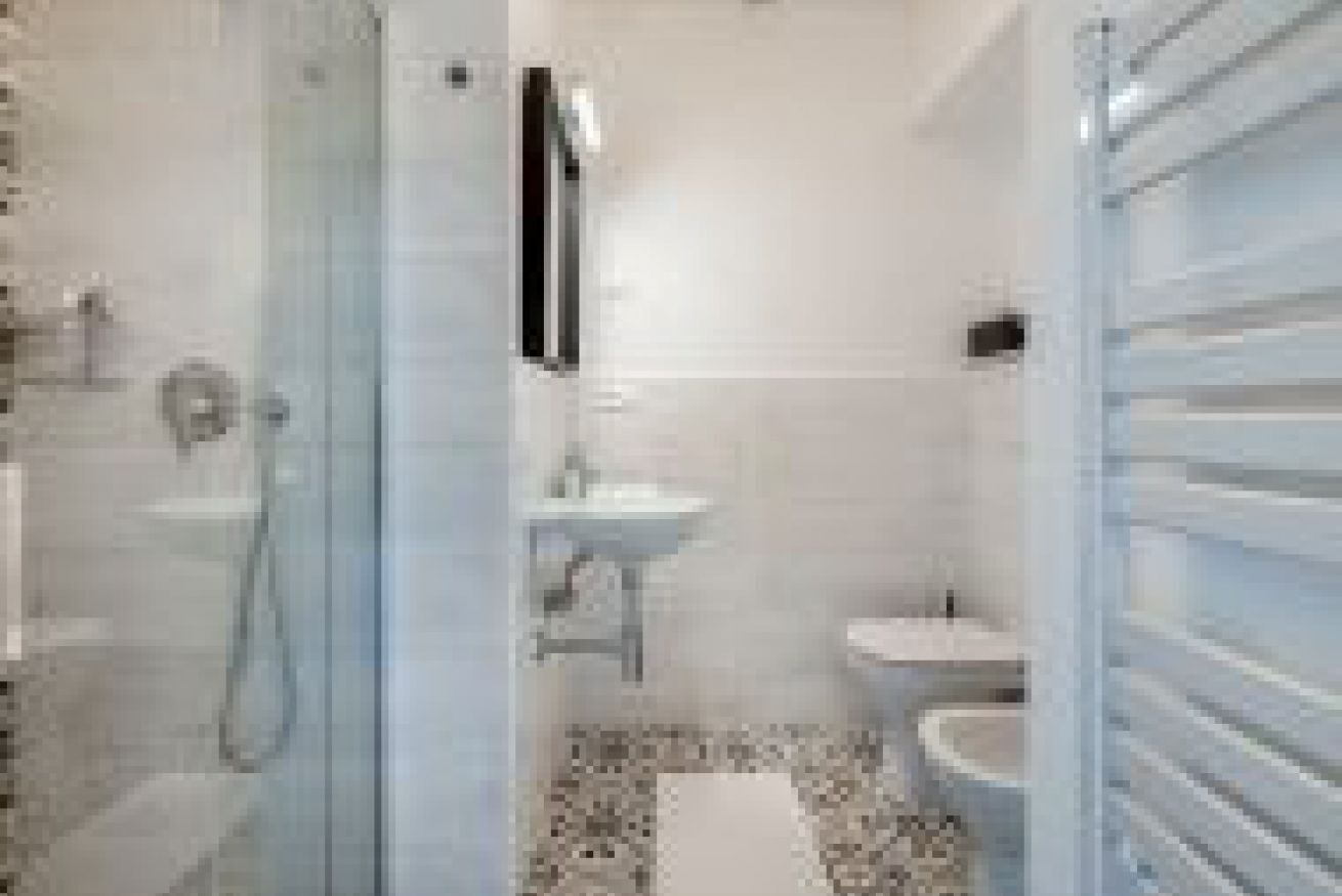 A bathroom with a glass shower enclosure, a sink, and a toilet.