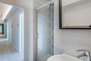 Ein Badezimmer mit Dusche, Waschbecken und Spiegel.