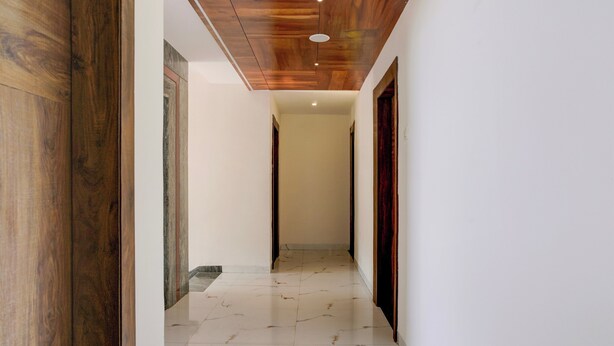 A hallway with wooden flooring, white walls, and a wooden ceiling. - Collection O Shirdi (Shirdi)