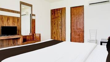 A hotel room with a large bed, a wooden desk, a television, and a wardrobe.