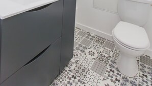Un baño moderno con un tocador blanco, un inodoro y un suelo estampado.