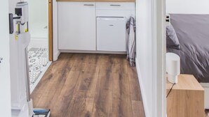 Cocina compacta con alacenas blancas, microondas, cafetera y lámpara colgante de fibra.