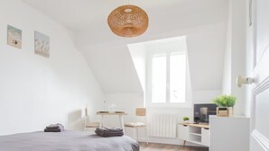 Un dormitorio con cama, escritorio, silla, ventana y lámpara colgante.