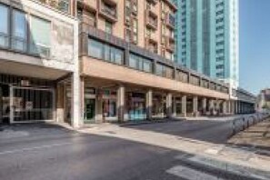 Ein mehrgeschossiges Hotel mit Geschäften im Erdgeschoss und einem Parkplatz.