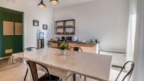 A modern kitchen with a dining table and chairs, a green door, and pendant lighting. - GuestHost - Family & Friends House - Spring Room (Padua)
