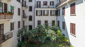 A courtyard with multiple balconies, potted plants, and a wooden pergola. - Italianway Comfort - Cellini 1 (Milan)