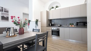 A modern kitchen with grey cabinets, a stainless steel oven, and a microwave. - Italianway Comfort - Cellini 1 (Milan)