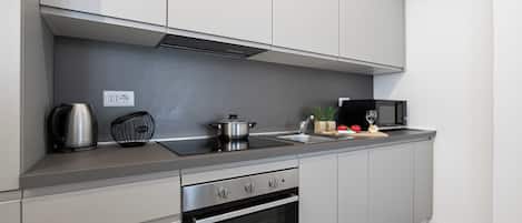 Een moderne keuken met een ingebouwde oven, een koffiezetapparaat, een magnetron en een pan op het aanrecht.
