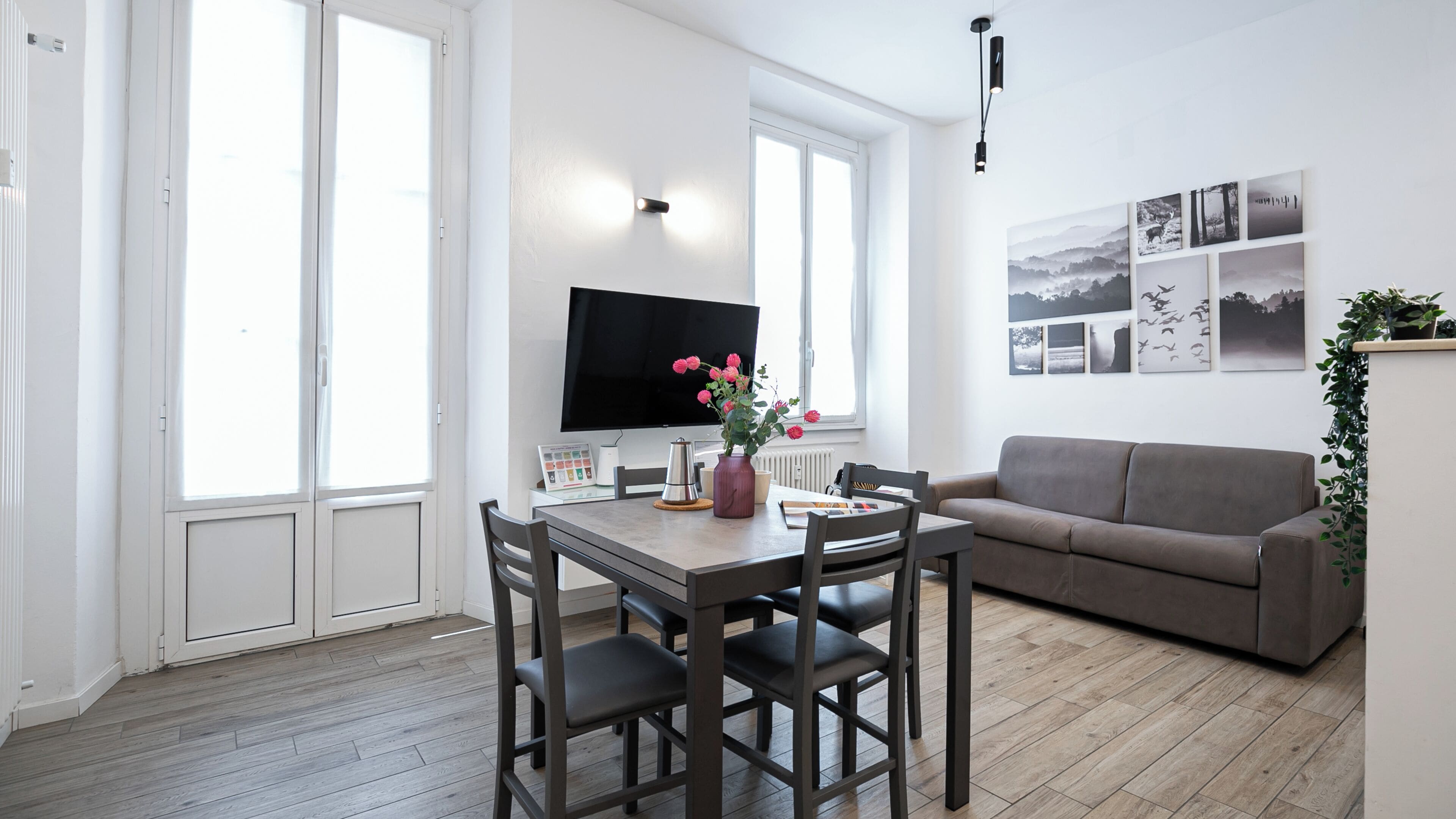 Un salon moderne comprenant un coin repas, un téléviseur à écran plat et un canapé.