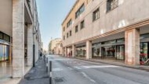A street with modern buildings, a clear sky, and a sidewalk. - GuestHost - Family & Friends House - Stanza Travel (Padua)