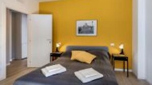 A bedroom with a bed, bedside tables, a door, and a wall-mounted picture. - GuestHost - Family & Friends House - Stanza Travel (Padua)