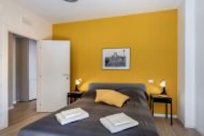 Ein Schlafzimmer mit einem Bett, Nachttischen, einer Tür und einem Wandbild.