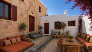 A courtyard with a seating area, a table, and potted plants. - Villa located in Lindos (Rhodes)