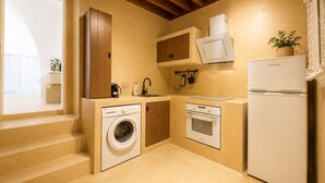 A compact kitchen with a washing machine, oven, and a built-in refrigerator. - Villa located in Lindos (Rhodes)