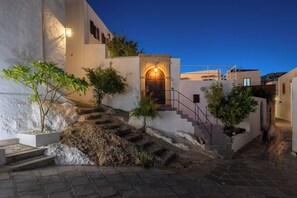 A narrow street with a staircase leading to a building with a lit entrance. - Villa located in Lindos (Rhodes)