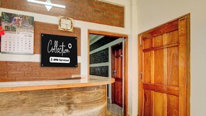 A reception desk with a wooden counter and a sign that reads 'Collection OYO-Serviced'.