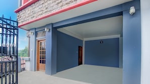 A building with a blue exterior, a wooden door, and a black metal gate.