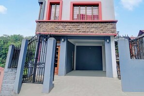 Edificio de dos pisos con fachada de piedra, entrada con puerta de rejas y garaje.
