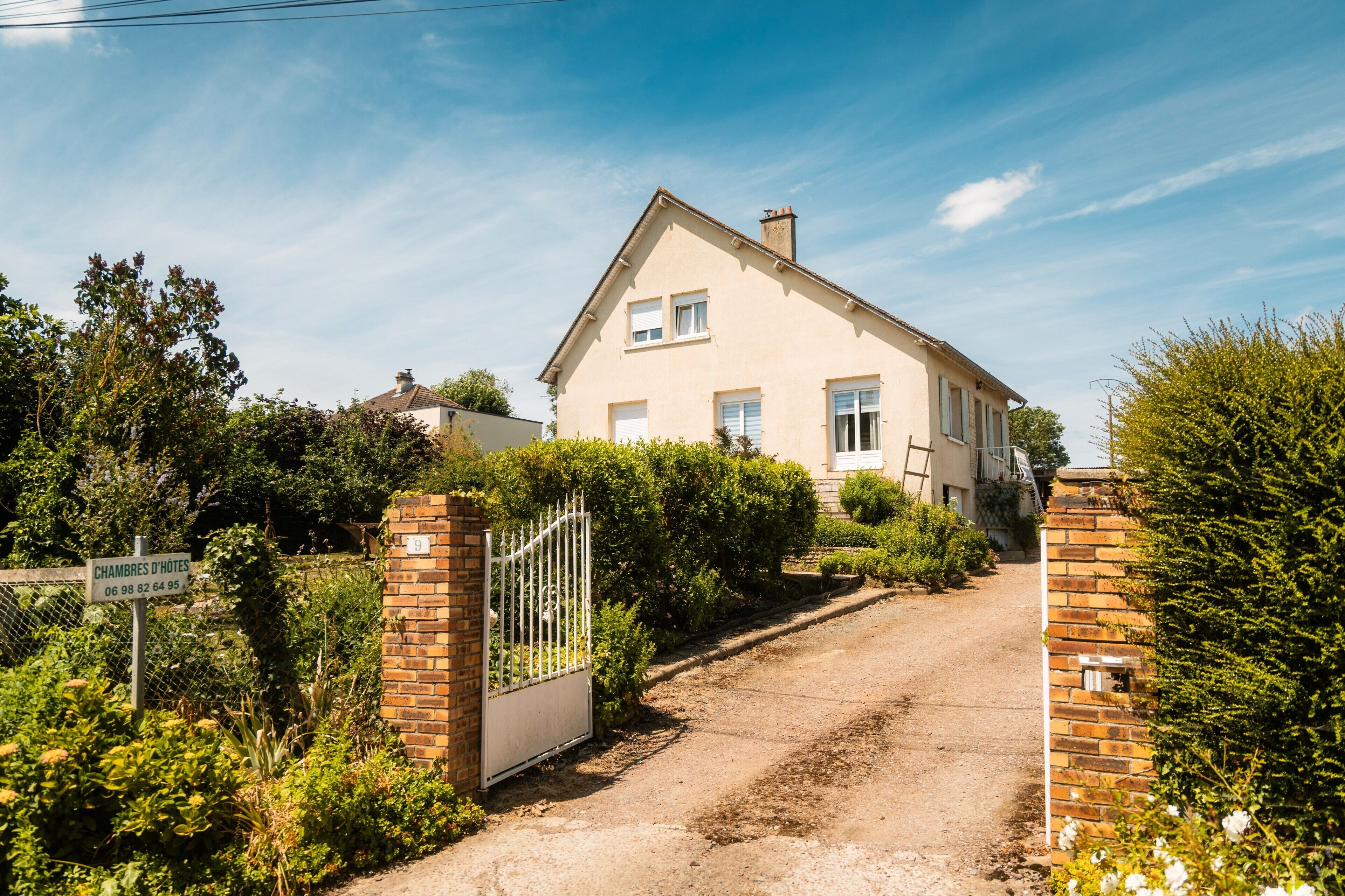 Een tweelaags huis met een verharde oprit naar een hekpoort.