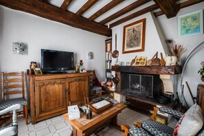 Una sala de estar acogedora con chimenea, muebles de madera, televisor y diversos objetos decorativos.