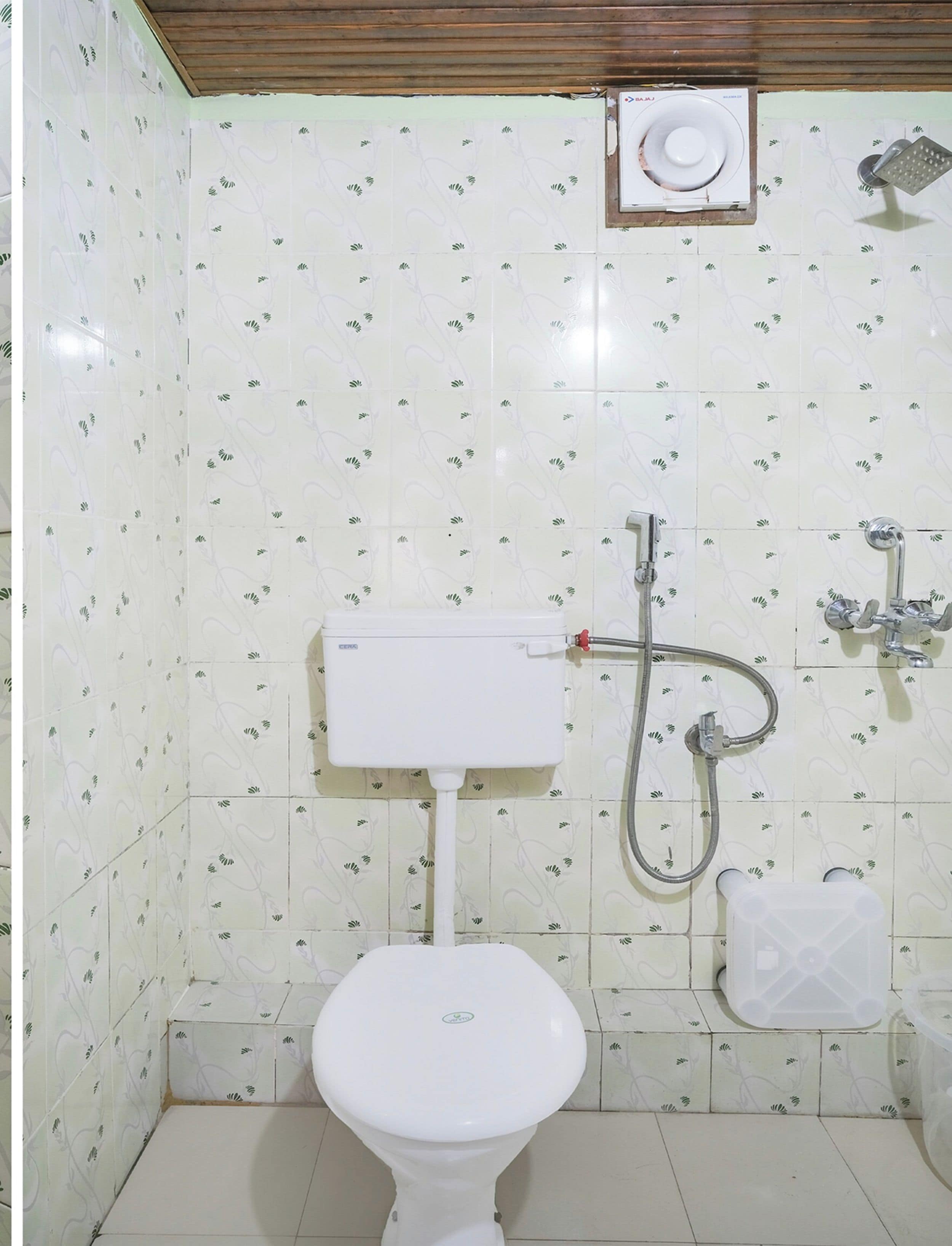 A bathroom with a toilet, a shower, and a toilet paper holder.