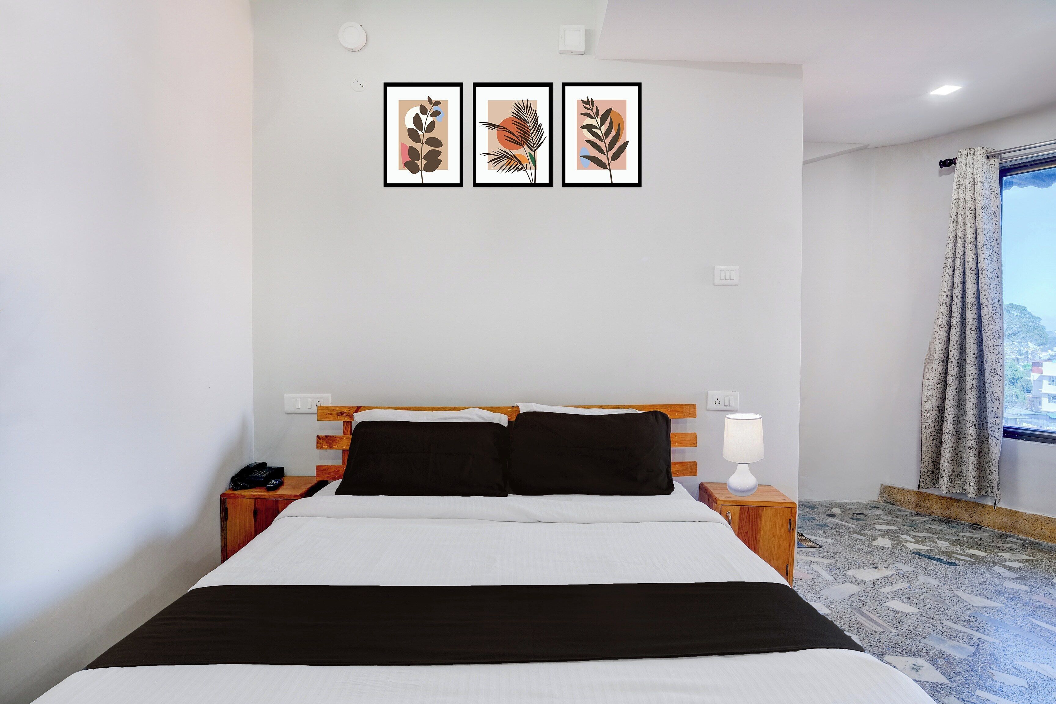 A hotel room with a bed, bedside tables, a lamp, and a window with curtains.