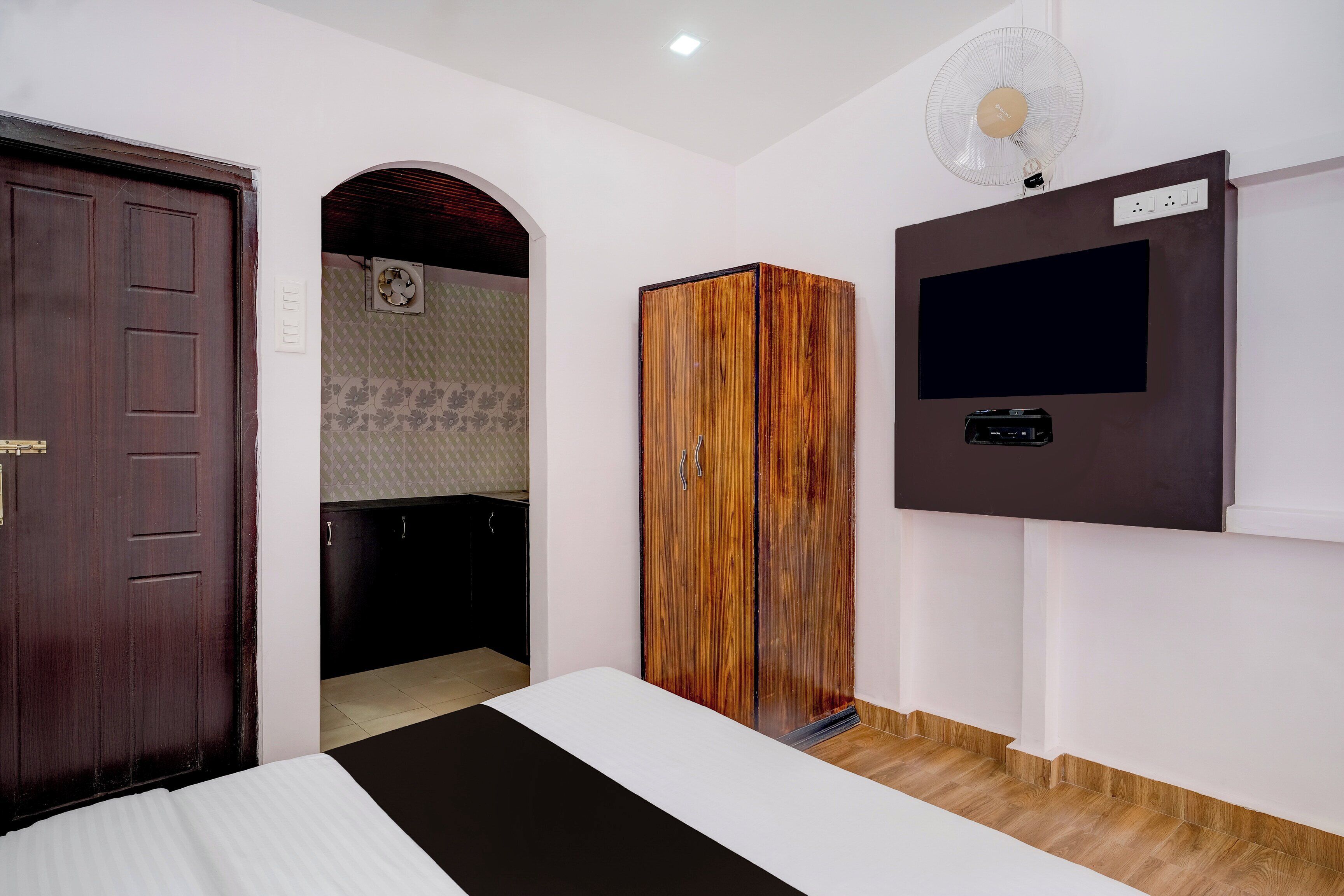A bedroom with a bed, wardrobe, TV, and a fan.