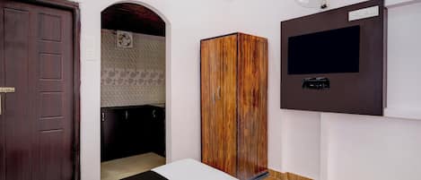 A bedroom with a bed, wardrobe, TV, and a fan.