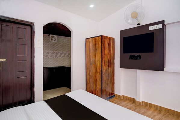 A bedroom with a bed, wardrobe, TV, and a fan.