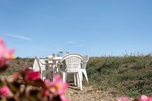 A white plastic table and chairs set outdoors with a clear sky in the background. - Duplex No. 2345 – 40m² – Seaside Residence (Port-des-Barques)