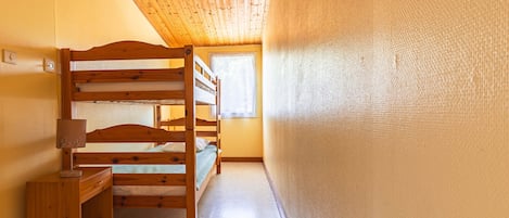 Un lit superposé avec une tête de lit en bois et une table de chevet avec une lampe.