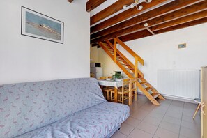 Une pièce avec un escalier en bois, une table à manger avec des chaises, un canapé et un radiateur.