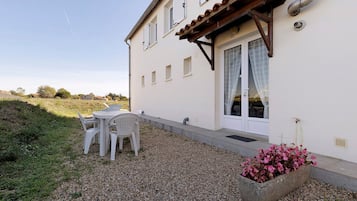 Un bâtiment doté d’un patio, d’une table avec des chaises et d’un jardinier.