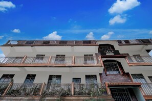 Un immeuble à plusieurs étages doté de balcons et d’une enseigne indiquant qu’il propose un service de collecte pour les entreprises.