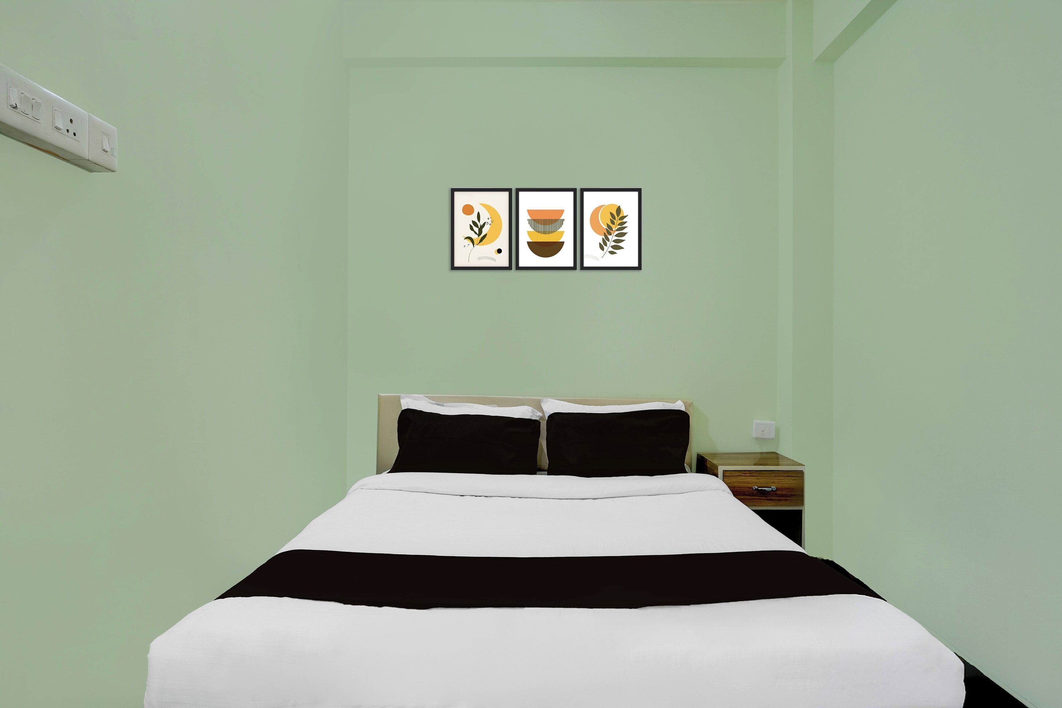 A room with a bed, a nightstand, and three framed pictures on the wall.