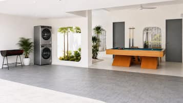 Espaço interior moderno com mesa de bilhar, máquina de lavar roupa e equipamento de snooker.