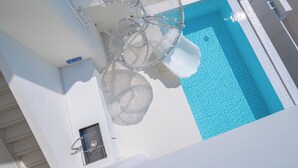 Vista despejada de una piscina con tobogán de vidrio y una fuente de agua.