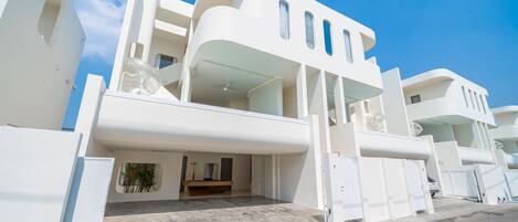 A modern white building with balconies and a covered entrance.