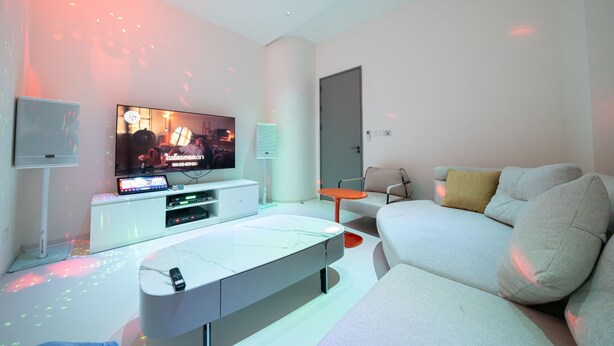 Una sala de estar moderna con un televisor de pantalla plana, un sofá blanco y una mesa de centro.
