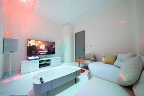 Una sala de estar moderna con un televisor de pantalla plana, un sofá blanco y una mesa de centro.