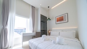 A modern hotel room with a large bed, a desk, and a view of the city.